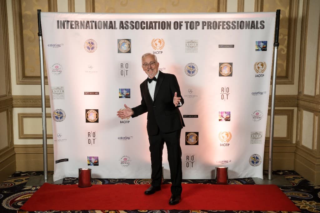 Prof. Larson in a tuxedo at the IAOTP gala step-and-repeat, Las Vegas 2025