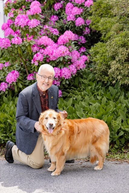 Prof. Larson with Maisie the golden retriever in the garden